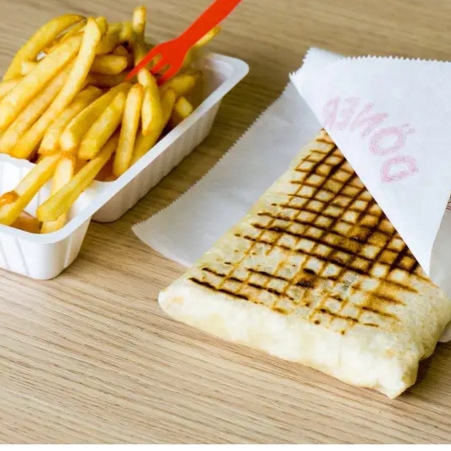 Tacos grillé servi dans son papier avec une barquette de frites